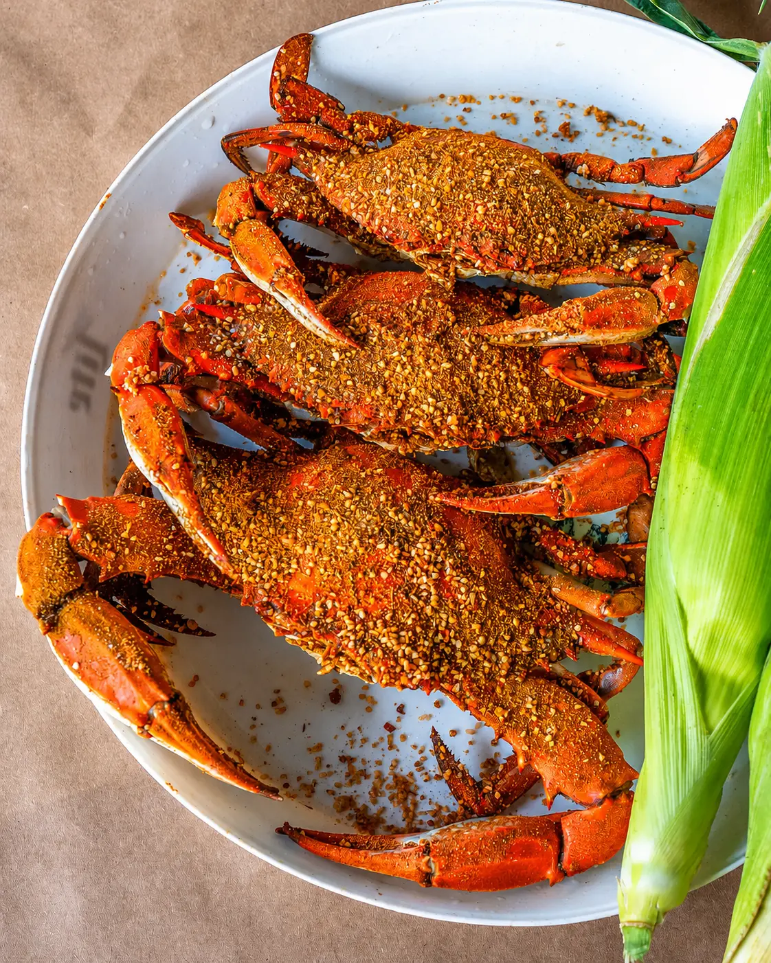 Fresh steamed Maryland blue crabs with Hooper's seasoning and corn on a white plate