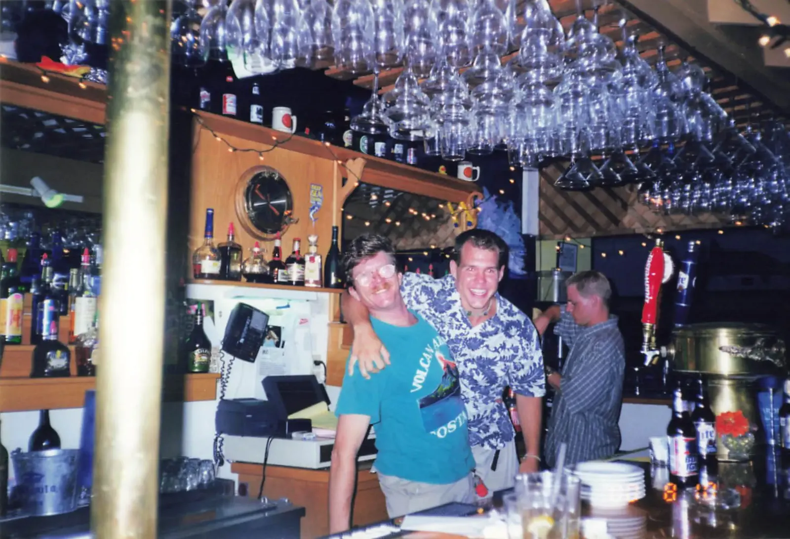 Hooper's Crab House bartenders behind the bar beneath rows of hanging glassware