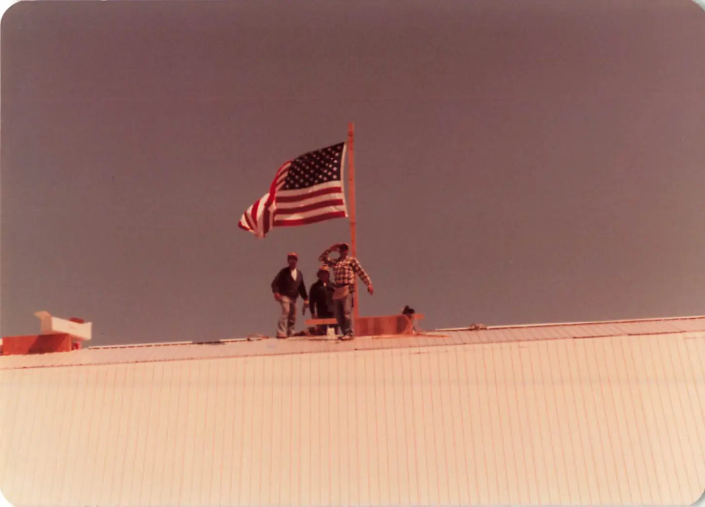 Workers raising an American flag on the roof of Hooper's Crab House during construction