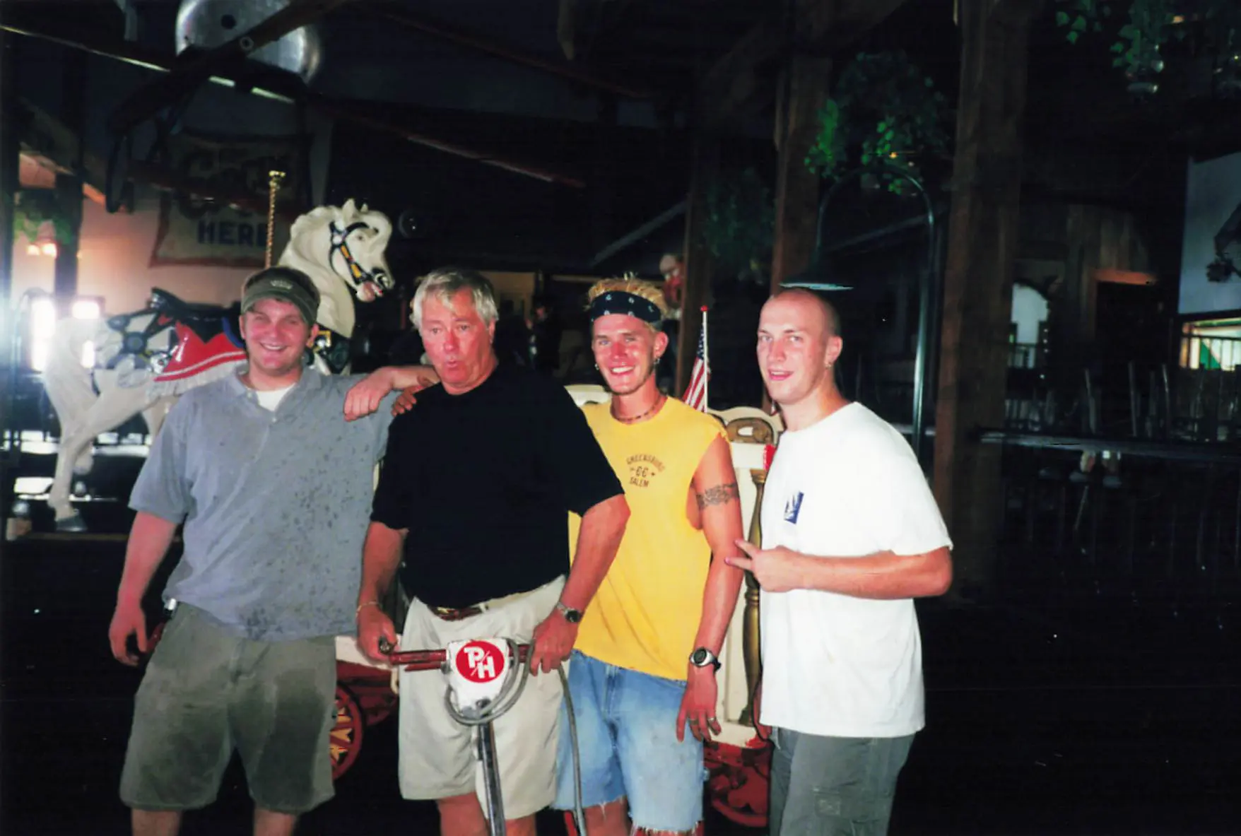 Pete Shepherd posing with three Hooper's staff members in front of the carousel horse inside the restaurant