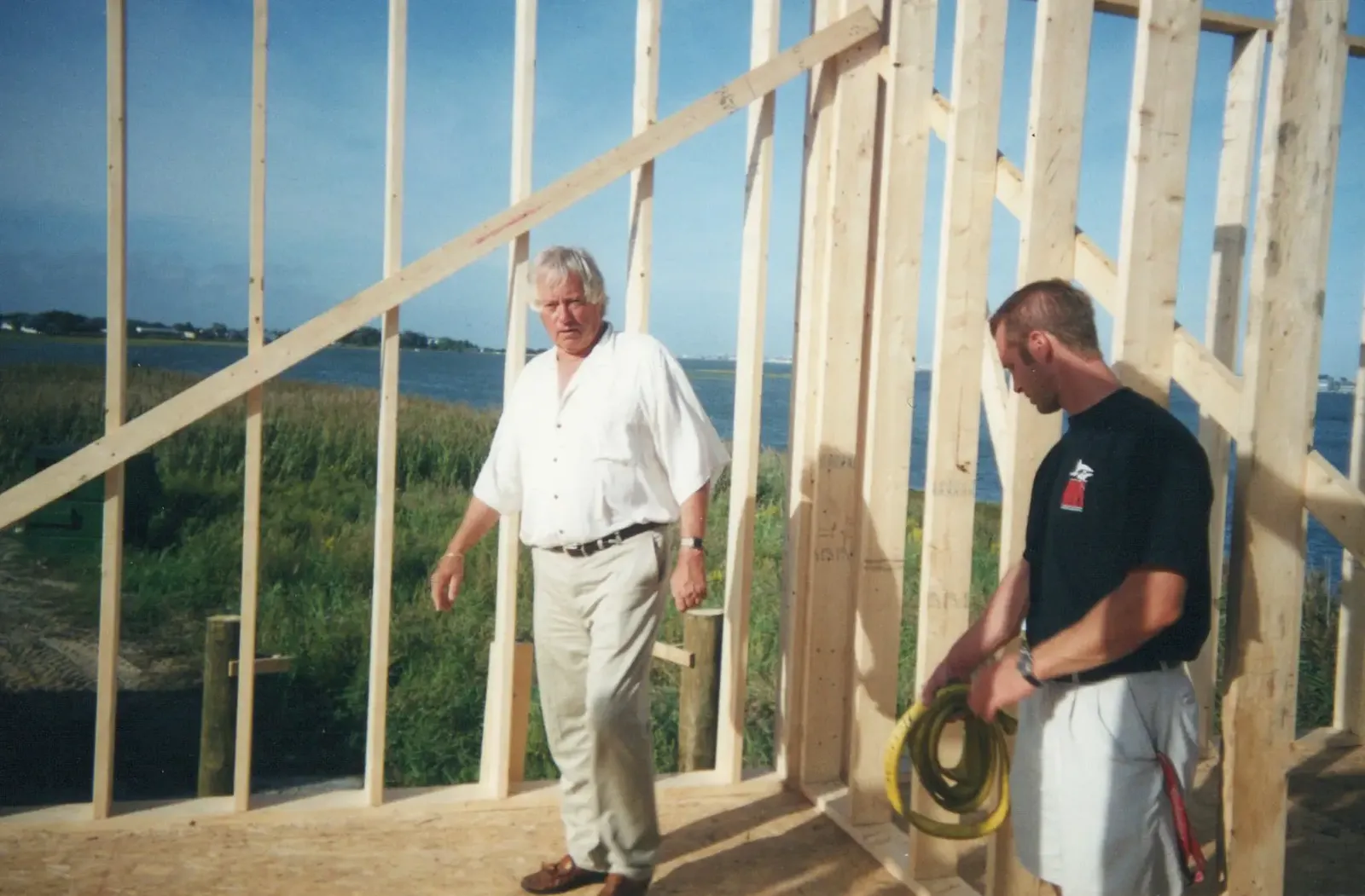 Pete and Ryan Shepherd inside the wood framing of Hooper's Crab House during rebuilding, with the bay behind them