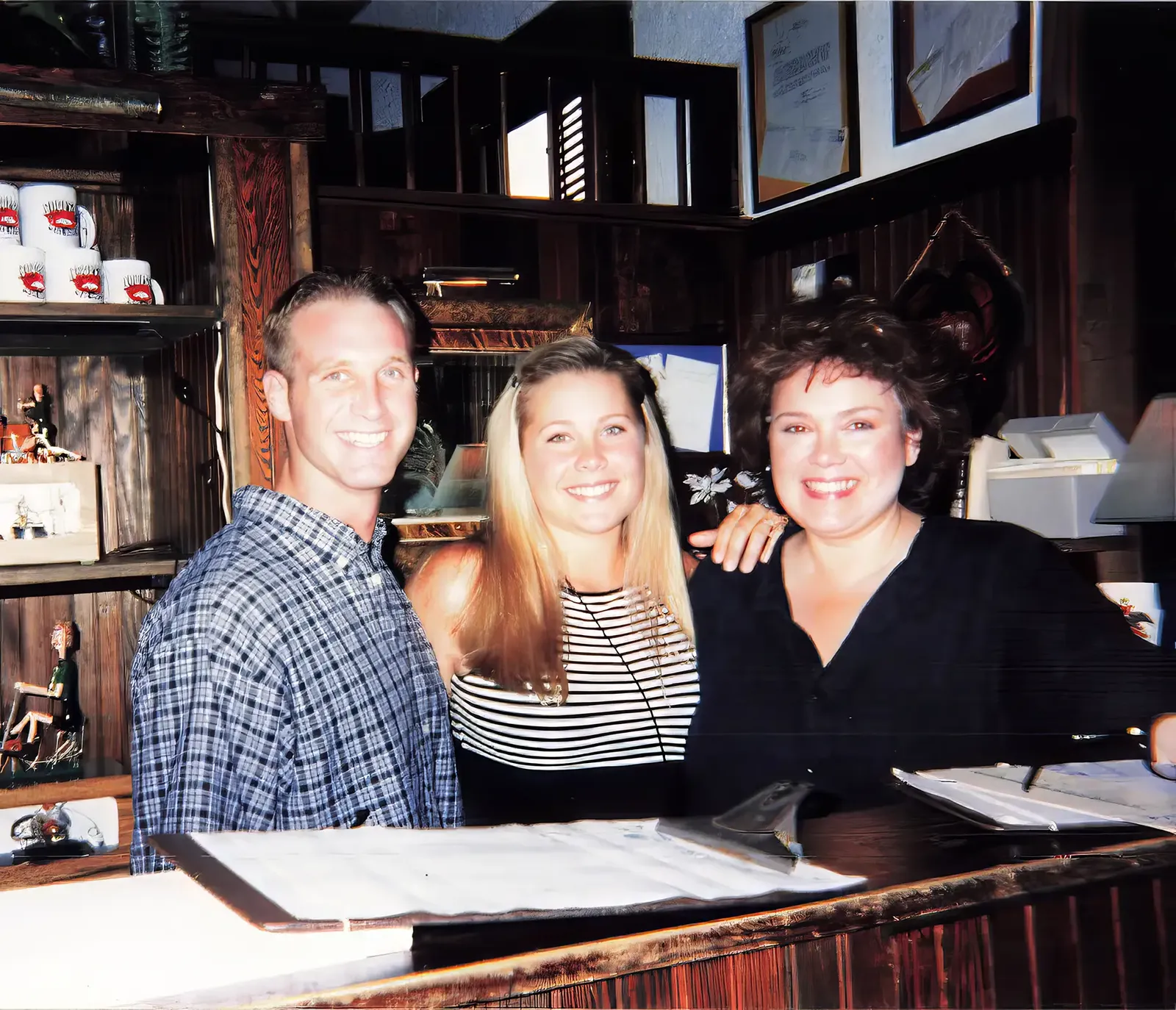 Ryan, a staff member, and Royette Shepherd smiling together at the Hooper's Crab House host stand