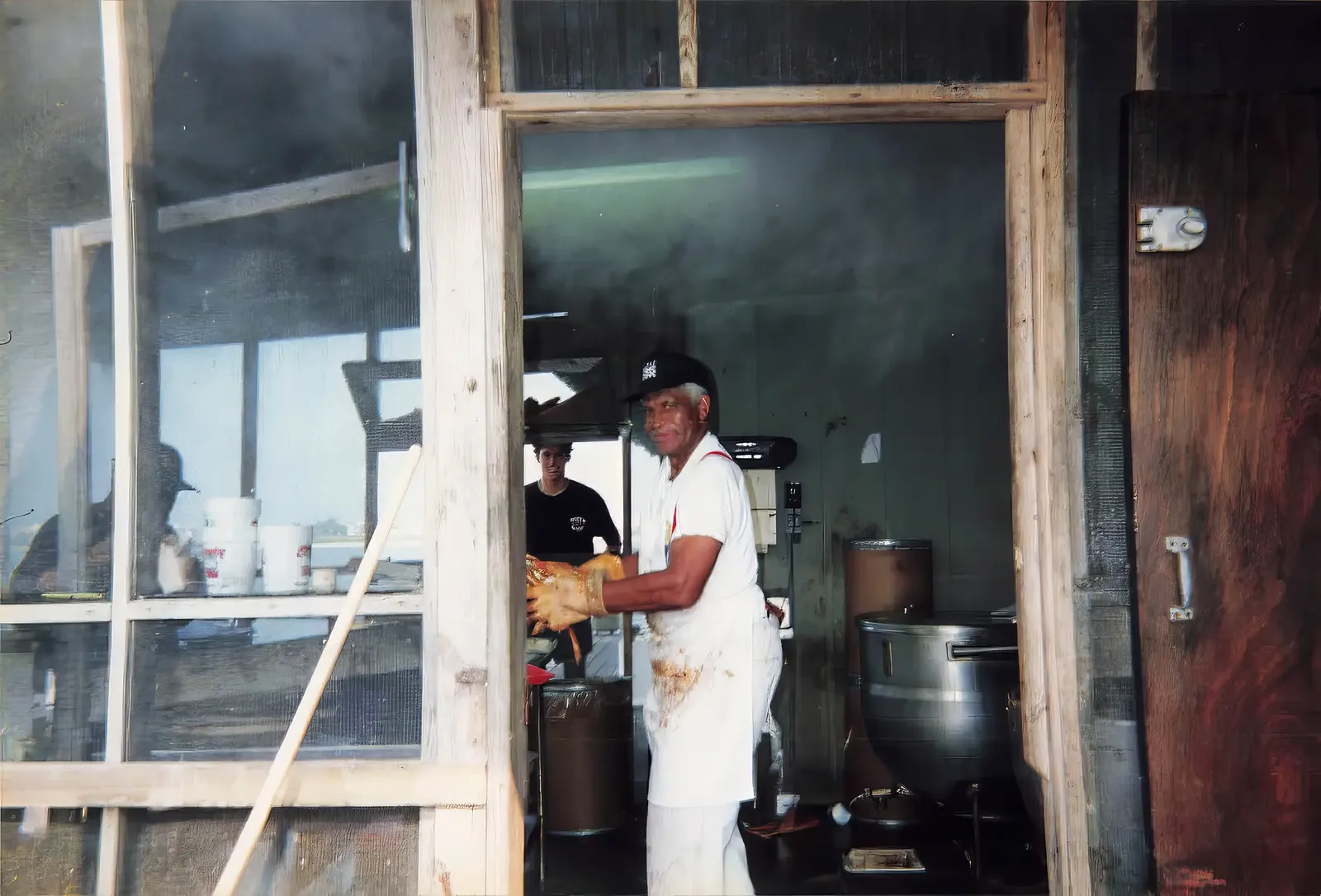 A Hooper's Crab House cook in an apron steaming crabs over large pots in the kitchen